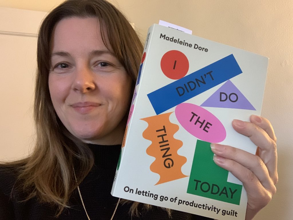 Photo of a smiling woman holding up a colourful book called "I didn't do the thing today"