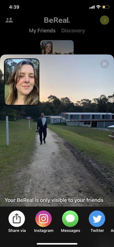 Screenshot of the BeReal app showing a dapper man on a path holding a camera, and a selfie of a woman in the top left corner