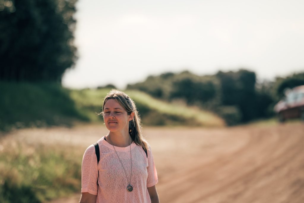 Photo of a woman taking a walk in nature with her eyes closed and half a smile