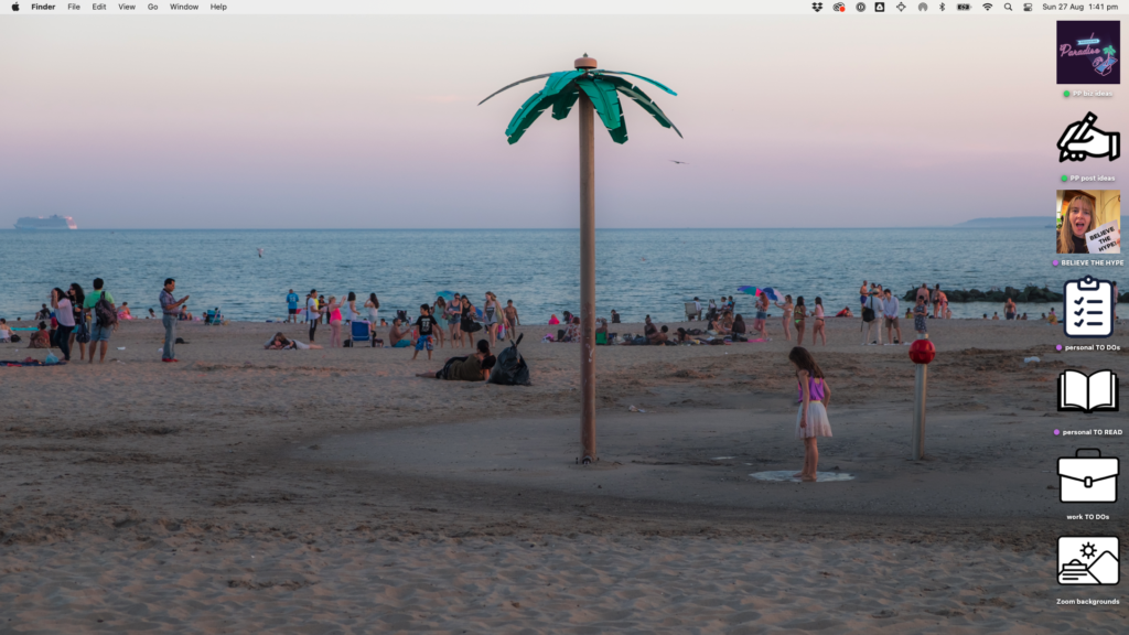 Photo of a dusk beach scene full of people relaxing and a metal palm tree planted in the middle
