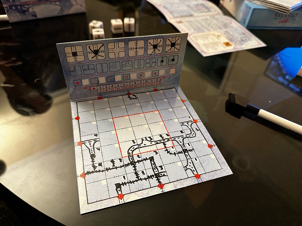 Photo of a board game player board showing hand drawn roads and railway lines